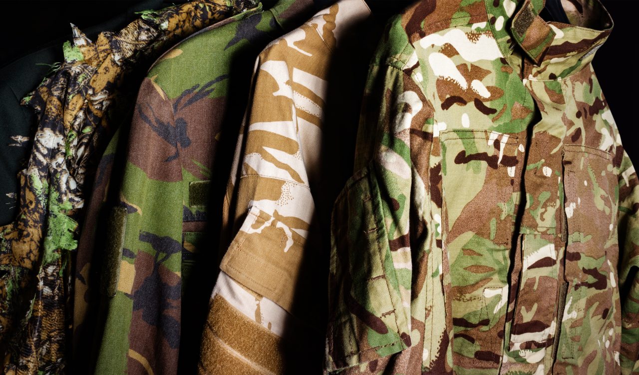 Photo,Of,A,Hanging,Military,Camouflaged,Jackets,On,Black,Background.