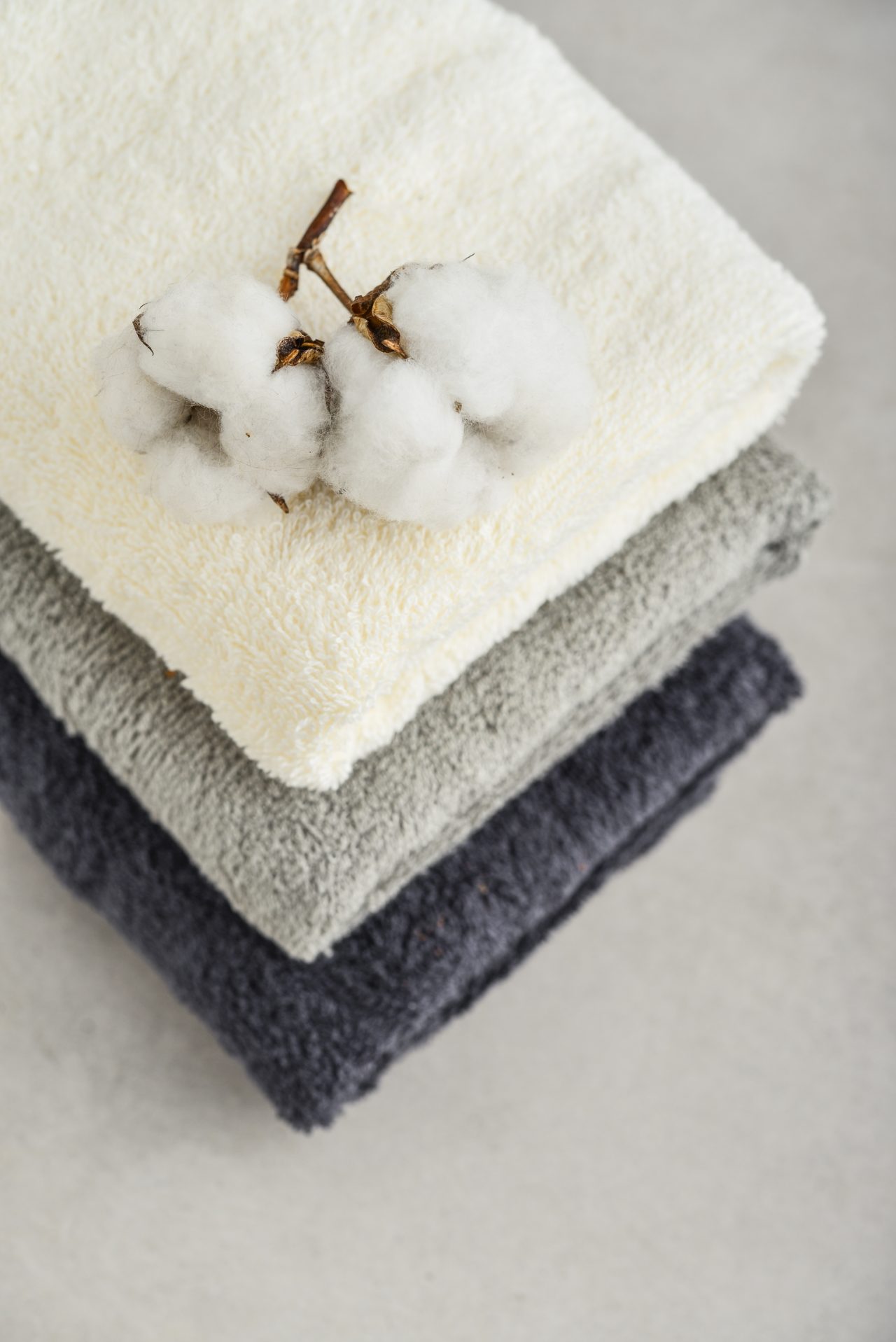 Stack,Of,Bath,Towels,With,Cotton,Flowers,On,Light,Concrete